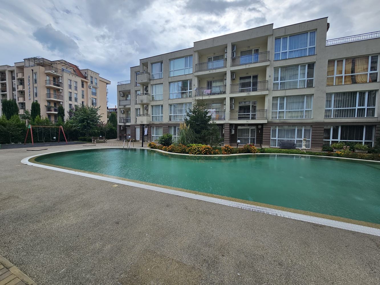 One-bedroom apartment surrounded by greenery in a complex with a swimming pool and children's playground