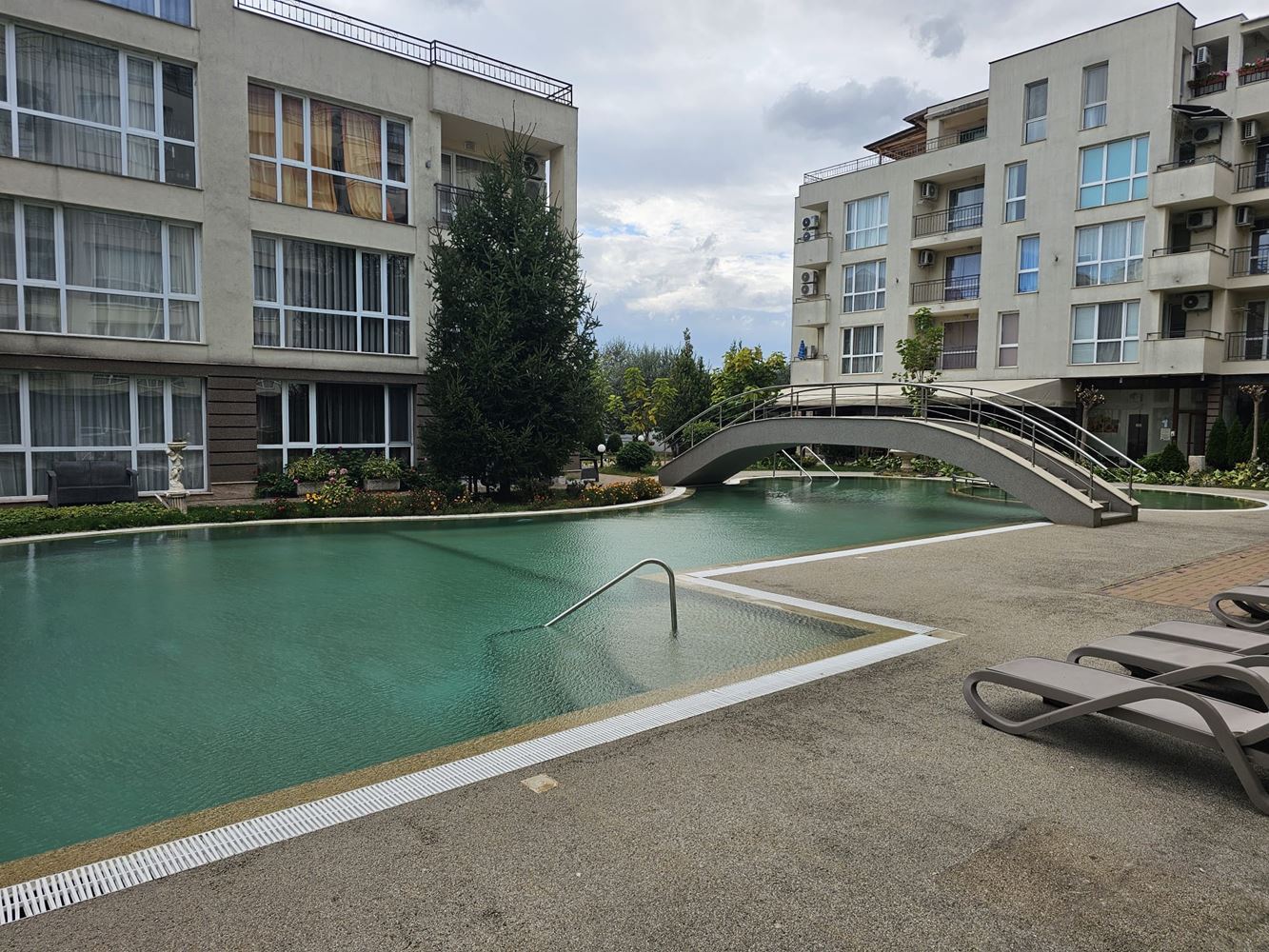One-bedroom apartment surrounded by greenery in a complex with a swimming pool and children's playground